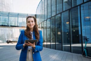 Real estate relocation expert in Dublin Ireland holding Ipad in front of modern building.